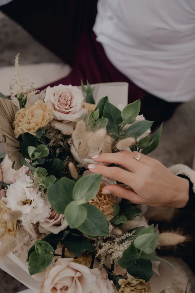 Pierścionek zaręczynowy i bukiet kwiatów na plaży