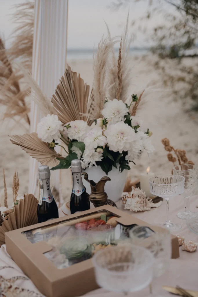 Aranżacja pikniku na plaży z kwiatami i winem