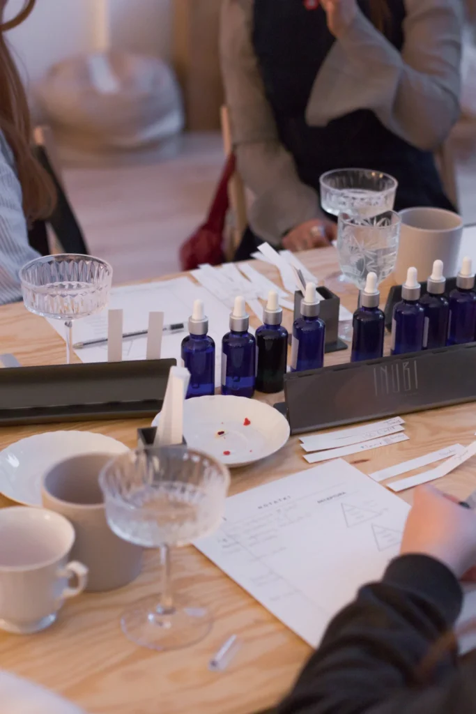 Uczestniczki warsztatów siedzące przy stole z materiałami edukacyjnymi i zapachowymi olejkami