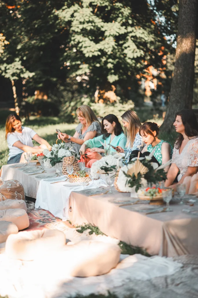 Kobiety przy wspólnym stole podczas pikniku biznesowego w plenerze, naturalna aranżacja i letnia atmosfera