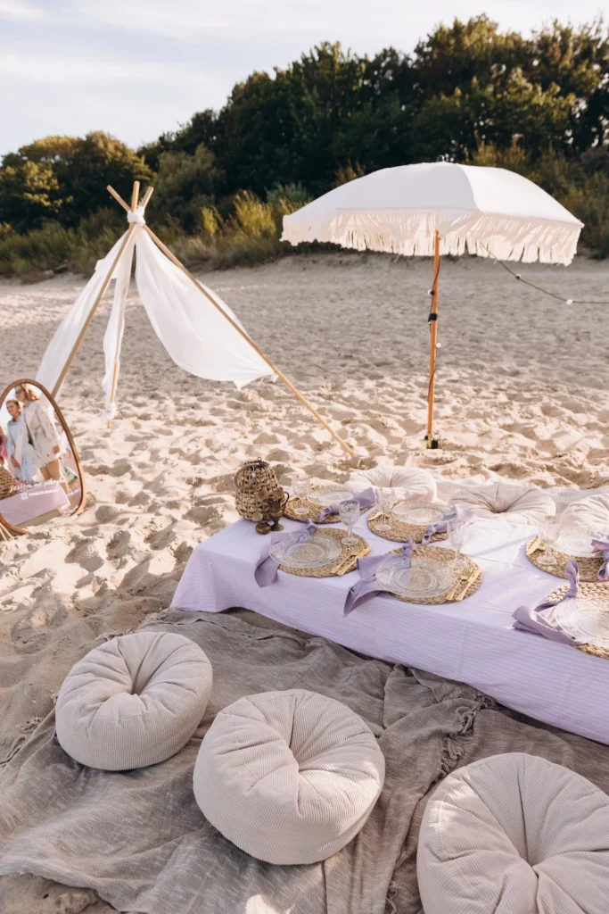 Piknik na plaży z niskim stołem, poduszkami i dekoracjami w stylu boho