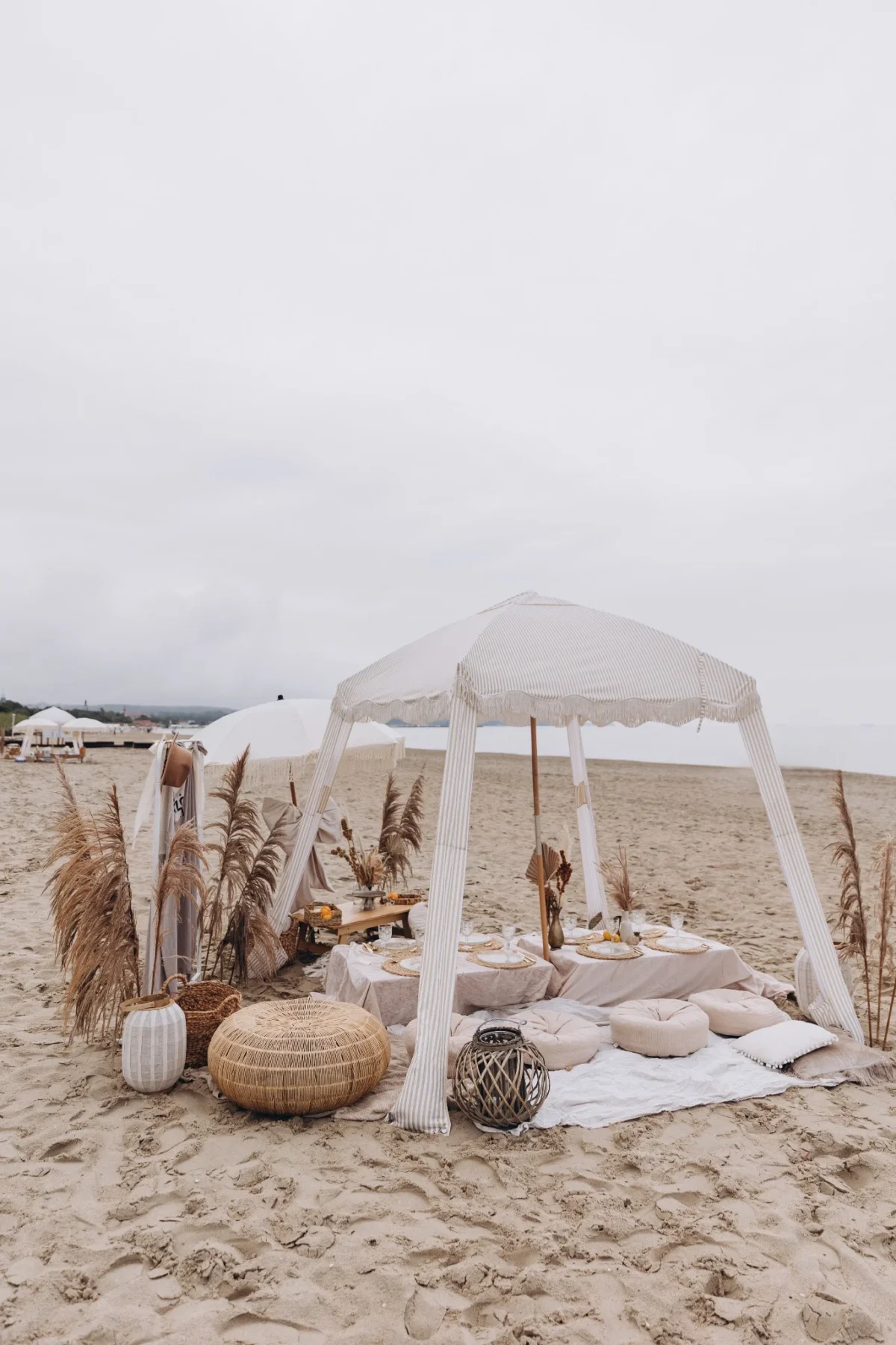 Aranżacja pikniku na plaży pod baldachimem z jasnych tkanin na plaży w Gdańsku