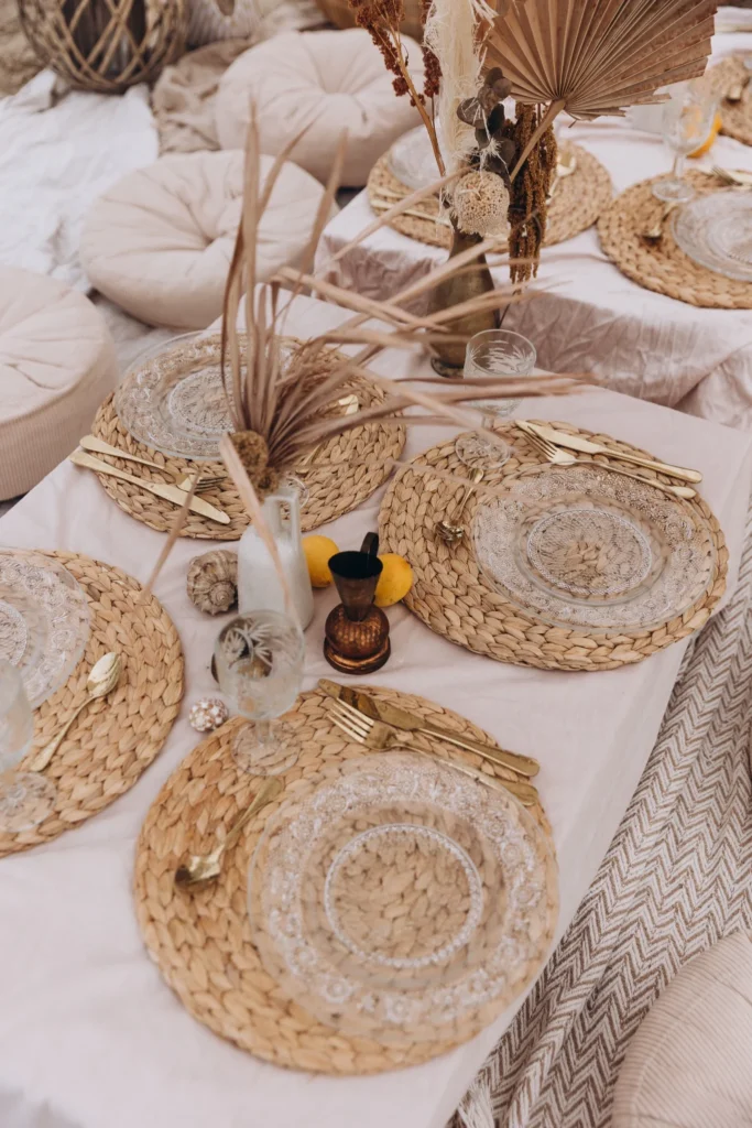Detale stołu piknikowego – plecione podkładki, szkło i naturalne dekoracje