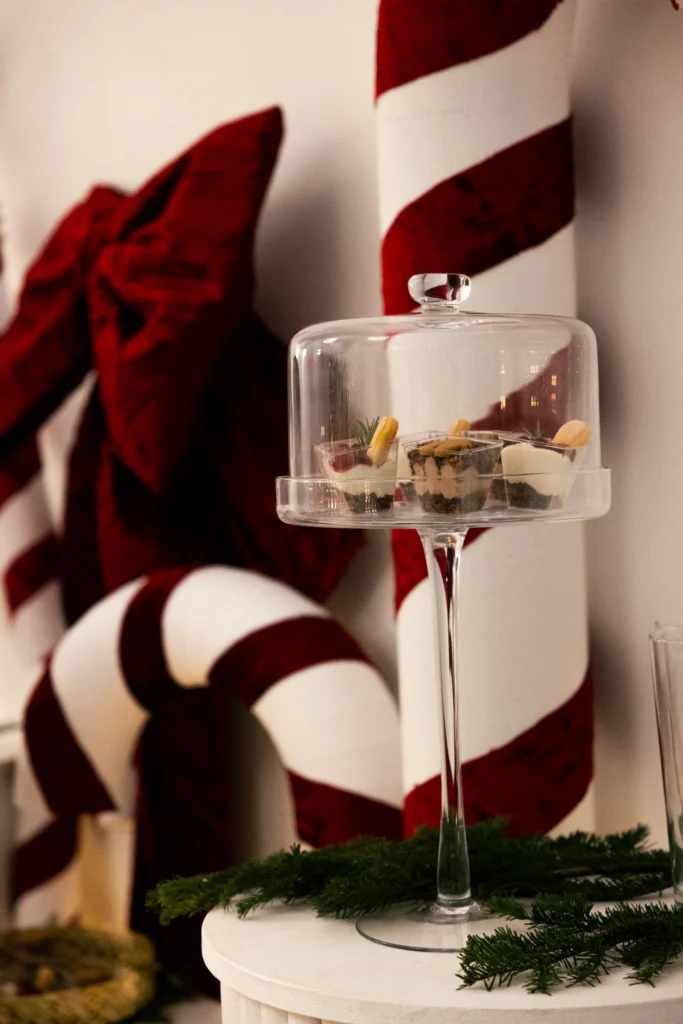 Świąteczna aranżacja stołu z deserami pod szklanym kloszem, dekoracje w czerwono-białym klimacie