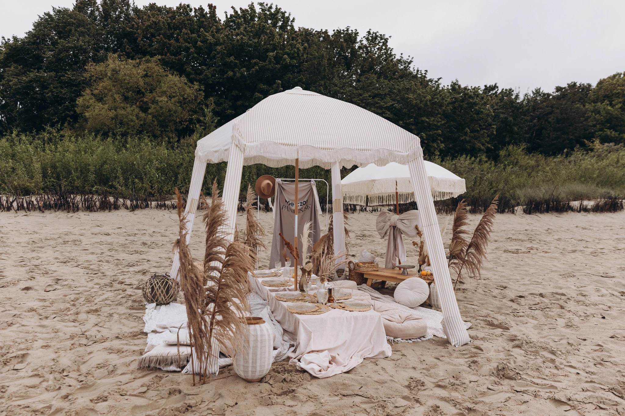Piknik na plaży w namiocie glampingowym – dekoracja boho, niskie stoły i strefa chillout, Chabazie